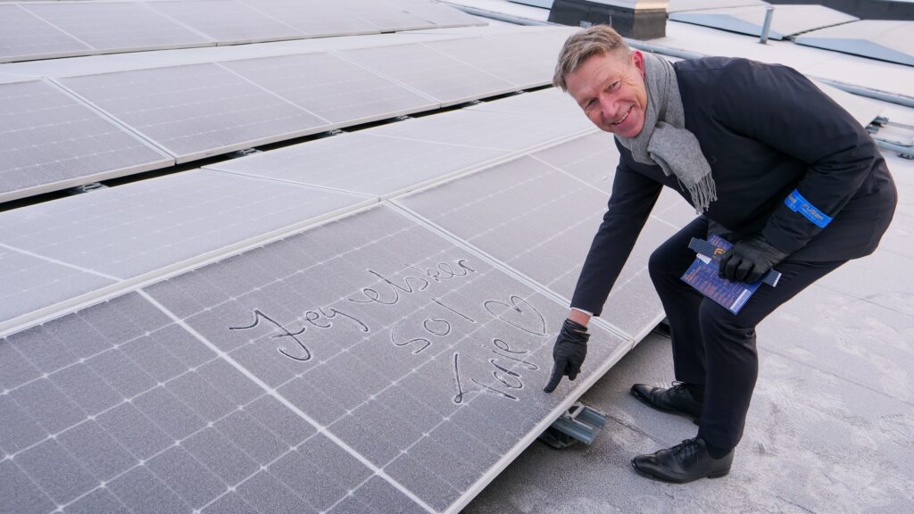 Energiminister Terje Aasland signerer et solcellepanel på taket av Alna Senter.